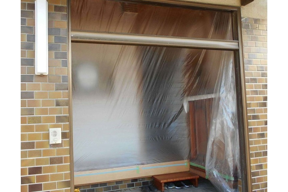 施工途中①：既存の玄関ドアを撤去し、養生作業を行っています。の画像